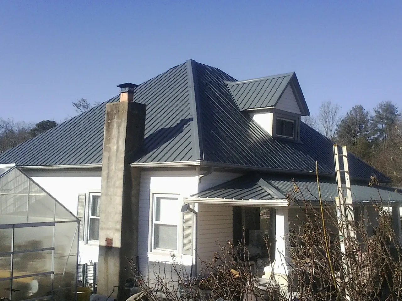 Dark blue standing seam metal roof on a white farmhouse with dormer — Slate & Tile Roof Repair by Roofing Brothers in Banks