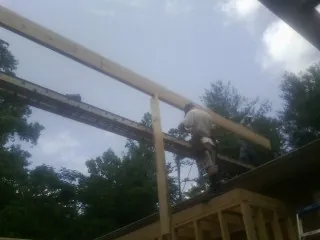 Carpenter setting a ridge beam over a new addition frame — Ice Dam Removal by Roofing Brothers in Banks