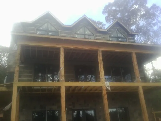 Dormers and porch framing on a large log home under construction — Roof Coating work by our crew in Banks