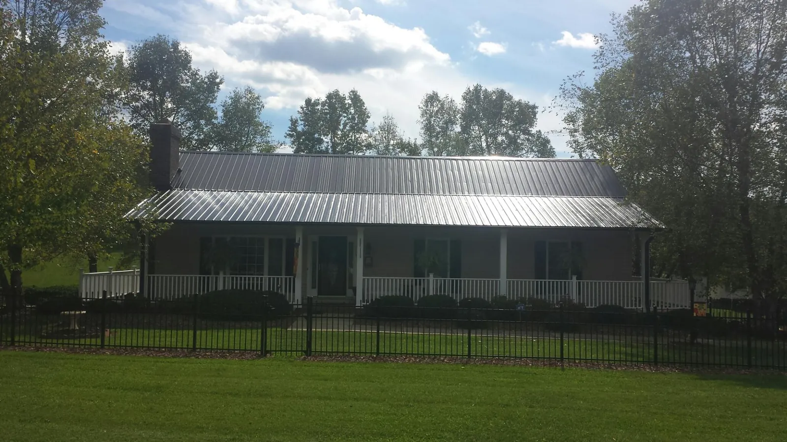 Gray metal roof on a brick ranch with a full width front porch — Gutter Guard Installation work by our crew in Banks